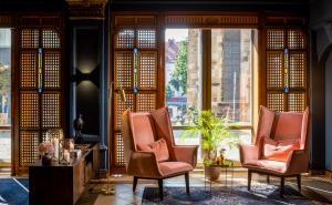 a room with two chairs and a table and windows at Van der Valk Hotel Hildesheim in Hildesheim