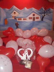 a table with red and white balloons and a painting of a house at B&B al Buondì in Camporosso in Valcanale