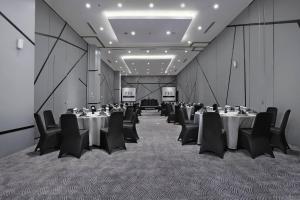 a conference room with tables and chairs and a screen at Hotel Neo Gajah Mada Pontianak by ASTON in Pontianak
