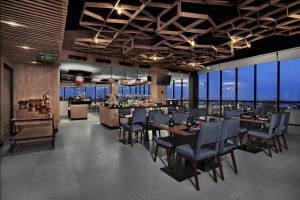 a restaurant with tables and chairs and a bar at Hotel Neo Gajah Mada Pontianak by ASTON in Pontianak