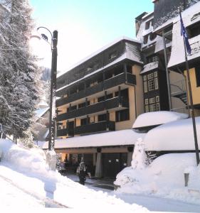 a building covered in snow next to a street at R.T.A. Hotel des Alpes 2 in Madonna di Campiglio
