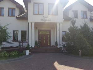 a white house with a front door with a bike parked in front at Białe Wzgórze in Okonek