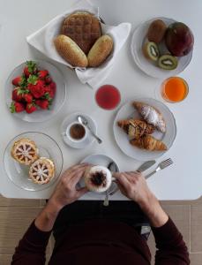 una persona sentada en una mesa con alimentos para el desayuno en Il Vigneto Resort en Menfi