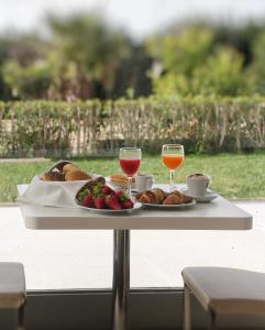 una mesa con dos copas de vino y comida. en Il Vigneto Resort, en Menfi