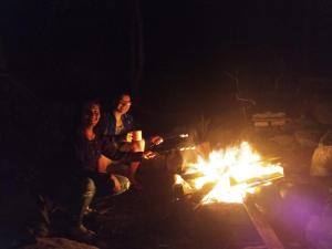 Trzech ludzi siedzących w nocy przy ogniu w obiekcie Camping Trópico de Capricórnio - Ilhabela w mieście Ilhabela