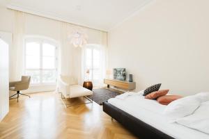 a white bedroom with a bed and a chair at Osteiner Hof by The Apartment Suite in Mainz