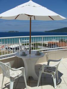 una mesa blanca con sombrilla en el balcón en Praia Pousada Tatuíra, en Florianópolis