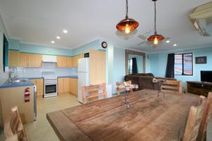 a kitchen and living room with a large wooden table at Bombora, 3/4 East Street in Crescent Head