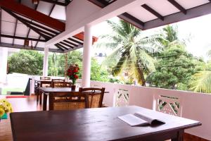 a restaurant with tables and chairs and a palm tree at Amal Guest house in Mirissa
