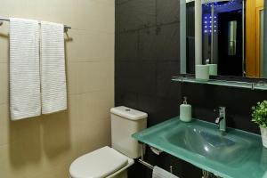 un bagno con un water, un lavandino e uno specchio di Aquele Cantinho ad Amadora