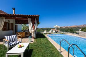 a villa with a swimming pool with a table and chairs at Kampos Villa III, pure elegance, By ThinkVilla in Achlades