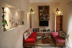 uma sala de estar com dois sofás vermelhos e uma televisão em Riad Couleurs du Sud em Marraquexe