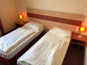 two beds in a hotel room with two lamps at Schleswig Holstein Hotel in Elmshorn