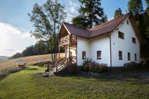 ein weißes Haus mit einem Holzdach auf einem Feld in der Unterkunft Pensjonat pod Górą Karczmisko in Konradów