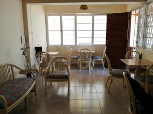 comedor con sillas, mesas y ventanas en The Base Backpackers, en Maputo