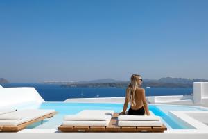 a woman sitting on a chair next to a swimming pool at Phos The Boutique in Akrotiri