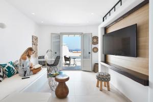 a woman sitting on a couch in a living room with a tv at Phos The Boutique in Akrotiri