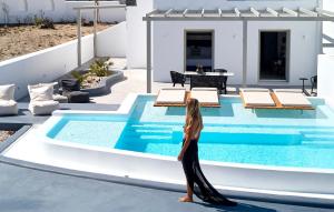 a woman standing in front of a swimming pool at Phos The Boutique in Akrotiri