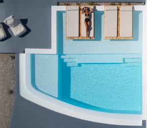a woman looking out of a window at a swimming pool at Phos The Boutique in Akrotiri