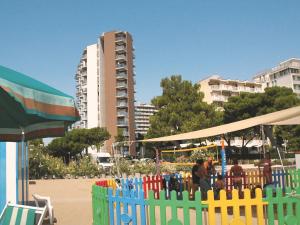 una recinzione colorata su una spiaggia con un edificio di Residenza Bianco Nero a Lignano Sabbiadoro