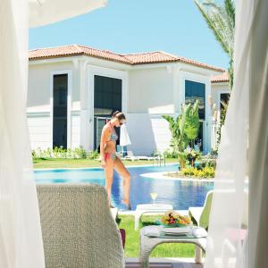 a woman in a bikini standing next to a swimming pool at Paloma Oceana - Luxury Hotel in Side