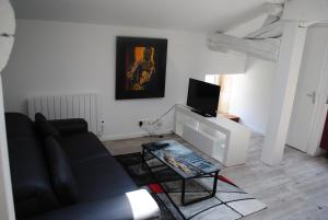sala de estar con sofá negro y TV en Ecurie de la Grange l'Abbé, en Le Langon