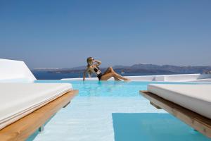 two women are sitting in the infinity pool at a resort at Phos The Boutique in Akrotiri