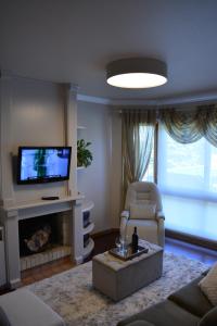 sala de estar con TV, sofá y silla en Condomínio Residencial Bugannvilias Flat en Gramado