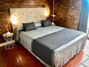 een slaapkamer met een groot bed met een bakstenen muur bij Teixidors de Palomar - PalomarGroup in Valencia