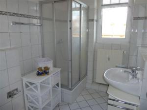 a white bathroom with a shower and a sink at Villa Nadine, gemütliche Ferienwohnung in Zingst