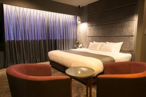 a hotel room with a bed and two chairs at Hotel Banister Kyoto in Kyoto