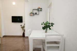 uma sala de jantar branca com uma mesa e cadeiras brancas em Apartman 1 em Zadar