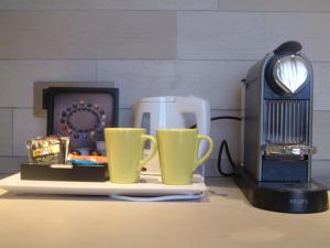 two yellow cups sitting next to a toaster and a microwave at Hotel Villa d'Elsa in Juan-les-Pins