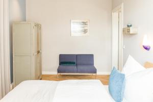 a bedroom with a bed and a blue chair at OSTKÜSTE - Nadler Hof Design Apartments in Ahlbeck +85 photos