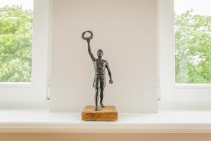 a statue of a person holding a clock in a window at OSTKÜSTE - Nadler Hof Design Apartments in Ahlbeck