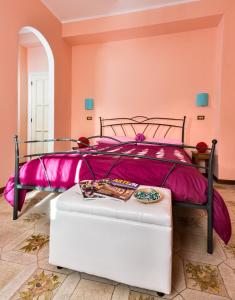 a pink bedroom with a bed and a white ottoman at La Villa in Pratola Peligna