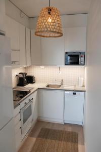 a kitchen with white cabinets and a pendant light at Nordic Apartment Rovaniemi in Rovaniemi +17 photos