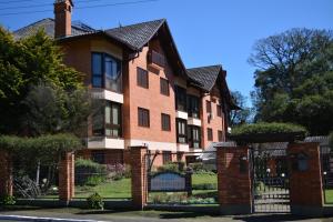 a red brick house with a black fence at Condomínio Residencial Bugannvilias Flat in Gramado