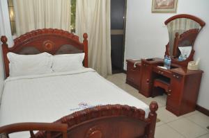 a bedroom with a bed and a desk and a mirror at Hotel de Mag Deluxe in Dar es Salaam
