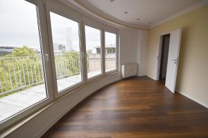 an empty room with large windows and wooden floors at Dorya am Ring in Cologne