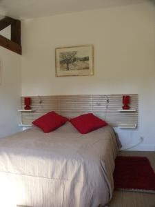 um quarto com uma cama com duas almofadas vermelhas em Gite de la Drouette et chambre d'hôtes em Villiers-le-Morhier