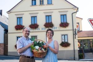 een man en een vrouw met een mand met groenten bij Hotel zur Linde in Gädheim