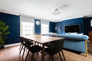 uma sala de jantar com paredes azuis e uma mesa e cadeiras em The Old Station House - Stylish & Central 2BDR Apartment em Oxford