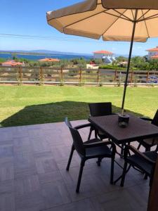 a table and chairs with an umbrella on a patio at Thealos Rooms in Vourvourou