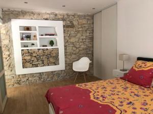 a bedroom with a stone wall and a bed and a chair at Clos Des Plages Maison De Vacances in La Ciotat