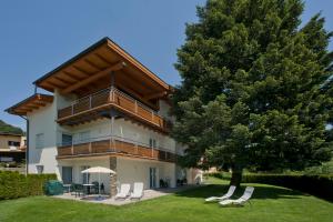 ein großes Gebäude mit Stühlen und einem Baum in der Unterkunft Apartments Hauskaernten in Velden am Wörthersee