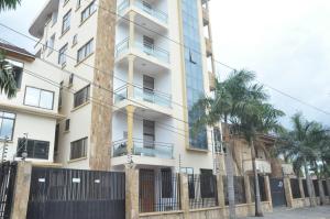 an apartment building with palm trees in front of it at Hotel de Mag (Plaza) in Dar es Salaam