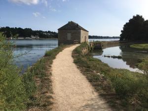 a dirt road leading to a building next to a river at Ker Mouettes in Arradon +15 photos