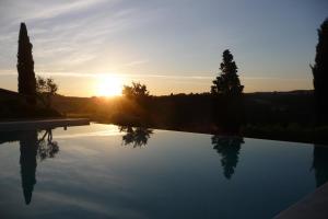 a swimming pool with the sunset in the background at Poggio ai Gelsi in Pienza