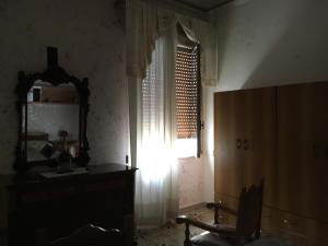 アヴォラにあるMar Ionio Apartmentの窓、鏡、椅子が備わる客室です。
